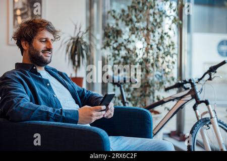 Happy businessman using smart phone in office Stock Photo