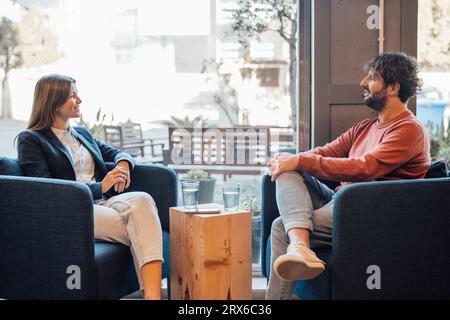 Smiling businessman people sitting on armchair and talking in office Stock Photo