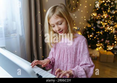 Girl playing piano at home on Christmas Stock Photo
