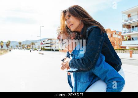 Senior man carrying woman piggyback and contemplating on footpath Stock Photo