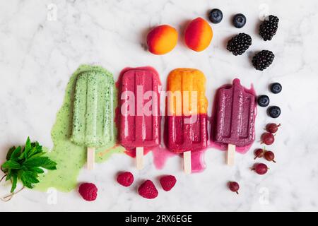 Berry fruits and melting popsicles on marble surface Stock Photo