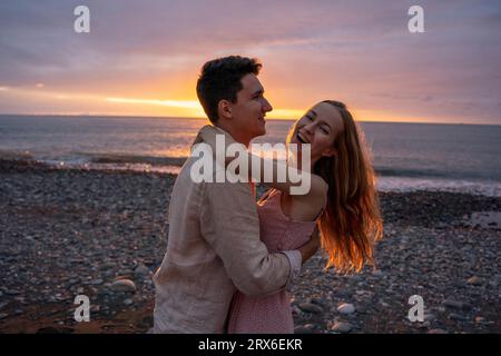 Happy young romantic couple dancing at beach on sunset Stock Photo