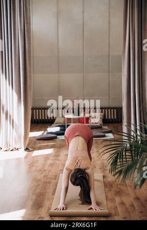Young woman practicing acroyoga on mat in health club Stock Photo