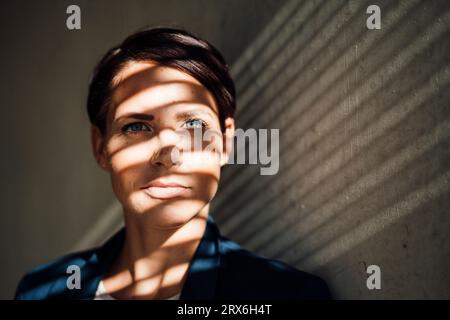 Businesswoman with shadow on face in front of wall Stock Photo