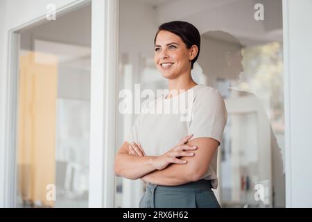 Smiling businesswoman with arms crossed standing in office Stock Photo
