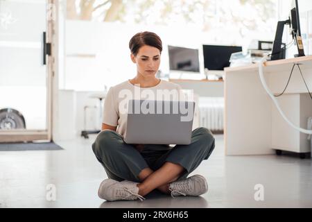 Businesswoman working on laptop sitting at workplace Stock Photo