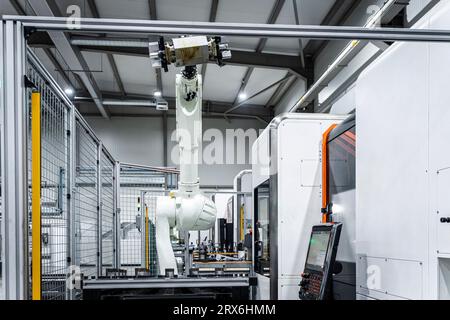 White robotic arm with cnc automated machinery in metal industry Stock Photo