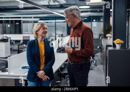 Smiling senior businessman discussing with colleague at work place Stock Photo