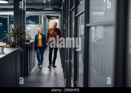 Business colleagues walking and discussing strategy in corridor at office Stock Photo