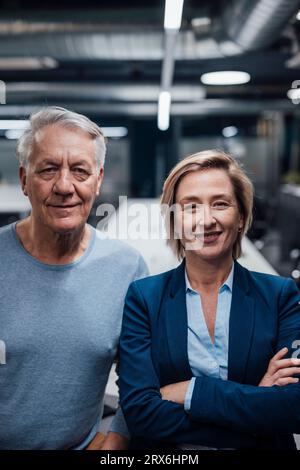 Smiling businesswoman with arms crossed by colleague in office Stock Photo