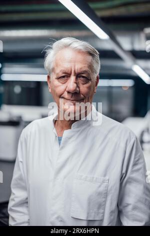 Smiling senior doctor wearing lab coat in clinic Stock Photo