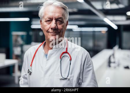 Smiling doctor with stethoscope and lab coat in hospital Stock Photo