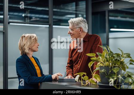 Smiling business colleagues discussing at work place Stock Photo