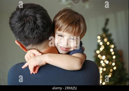 Father embracing smiling son at home Stock Photo