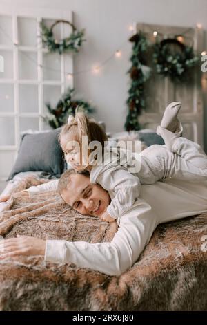 Playful father and daughter lying on bed at home Stock Photo
