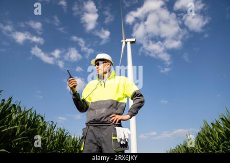 Engineer with walkie-talkie standing in field on sunny day Stock Photo