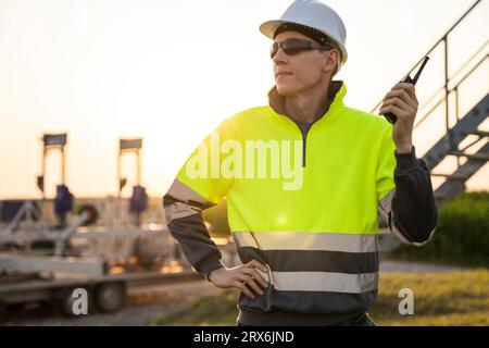Engineer holding walkie-talkie and standing in field Stock Photo