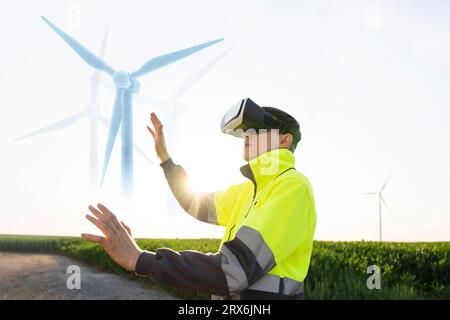 Engineer examining augmented wind turbine model through VR simulator on sunny day Stock Photo