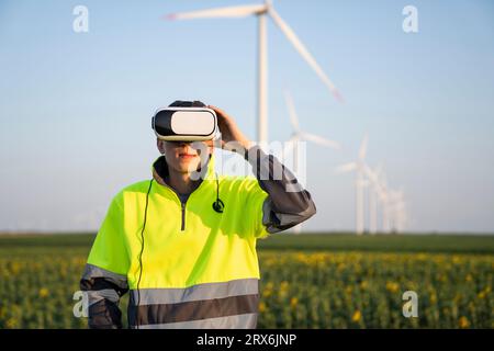 Engineer wearing virtual reality simulator standing in front of wind turbines Stock Photo