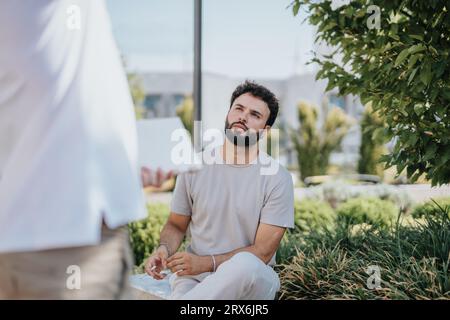 A team of architects and engineers collaborating outdoors, discussing a blueprint on a tablet for a building project in the city. Successful teamwork Stock Photo
