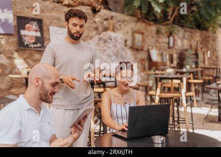A group of professionals brainstorm e-commerce strategies and analyze data in a cafe bar. They discuss trends, target audience, and online retail grow Stock Photo