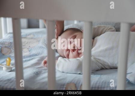 Baby girl sleeping in crib at home Stock Photo