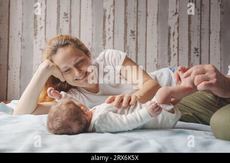 Mother playing with newborn daughter on bed at home Stock Photo