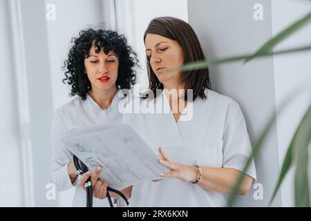In a healthcare workplace, two professionals discuss patients results, collaborate on medical outcomes, and work together to provide effective care. Stock Photo