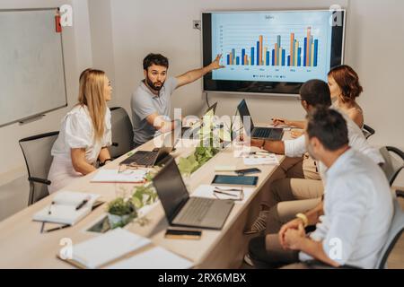 Diverse business team analyzing data in office workspace with technology and creative tools. Multicultural collaboration for profit growth. Stock Photo