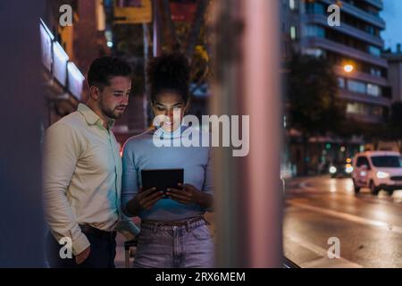 Businessman with colleague using tablet PC on street Stock Photo