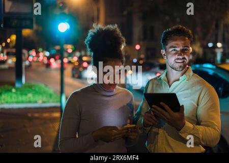 Businesswoman using smart phone with colleague holding tablet PC Stock Photo