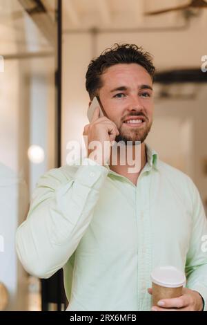 Smiling businessman talking on smart phone in cafe Stock Photo