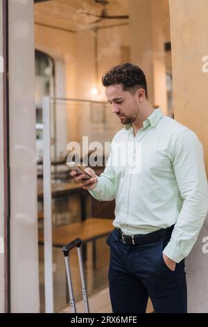 Young businessman using smart phone outside cafe Stock Photo