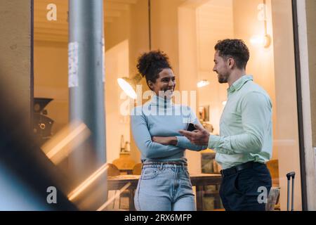 Happy young businessman talking to colleague outside cafe Stock Photo
