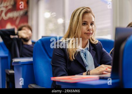 Female student working on her laptop with the other students while in class Stock Photo