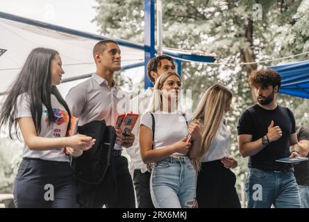 A diverse group of university students gathered in the campus yard, collaborating and discussing academics. Stock Photo