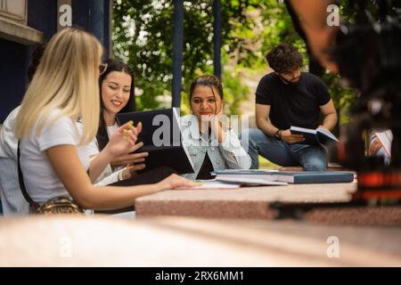 A diverse group of university students collaborating and exchanging ideas in a campus yard, preparing for exams and sharing knowledge. Stock Photo