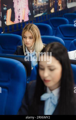Young and beautiful female student working on her laptops while attending class with her classmate in the foreground Stock Photo
