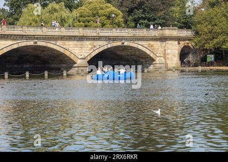 Group of friends in a pedalo boat on The Serpentine, Hyde Park. Serpentine Bridge in the background. Stock Photo