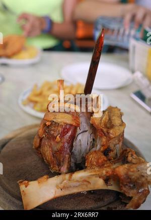 big roasted pork shank served on wooden cutting board in restaurant Stock Photo