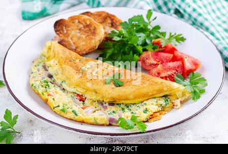Omelette with tomatoes, cheese and red onion on white plate.  Frittata - italian omelet. Stock Photo