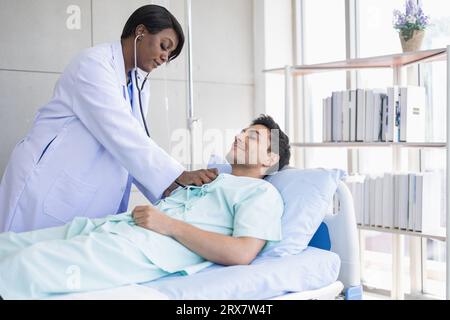 African doctor morning visit patient using stethoscope checking lung breath and heart pulse male in hospital Stock Photo