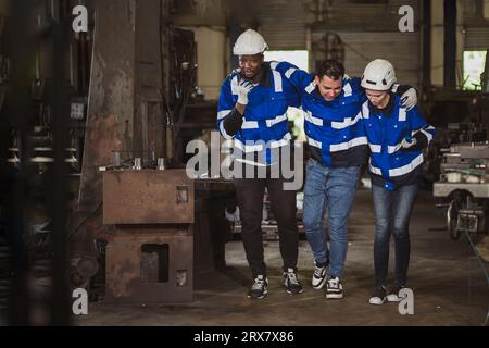 Engineer technician male worker leg ankle injury in dangerous industry workplace friend worker help support walk to medical room Stock Photo