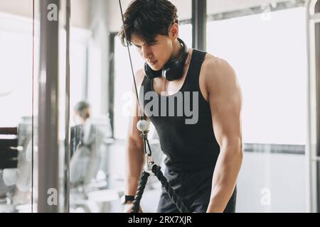 Young muscular man does lower chest exercises with machine in
