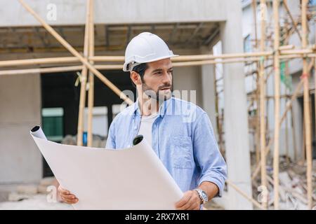 Construction engineer builder work in construction site. Architect home project foreman chief designer working with floor plan. Stock Photo
