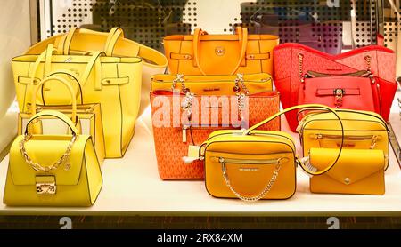 Shelf display of orange yellow and red handbags on sale in Michael