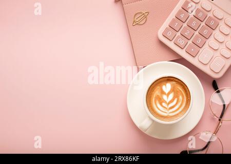 Calculator, a cup of coffee with a beautiful pattern and a notepad on a pink background. Place for text. High quality photo Stock Photo