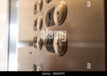 A close-up of an elevator control panel - stainless steel with round buttons - numbers and braille - emergency call and door open buttons Stock Photo