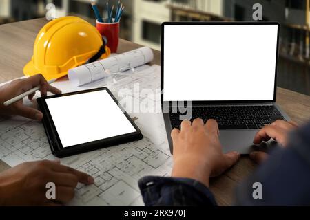 Engineer A construction technology worker checks an engineer using a computer on a construction site. Engineer teams in architecture, development, and Stock Photo
