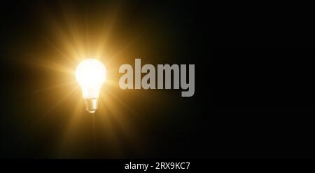 An illuminated or glowing lightbulb on a dark background represents new ideas, innovation, creativity, understanding, knowledge, and inspiration. Stock Photo
